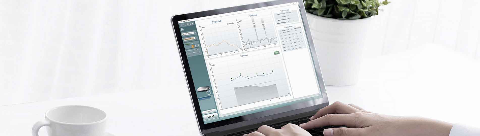 Clinician working on laptop which displays a passed DPOAE test