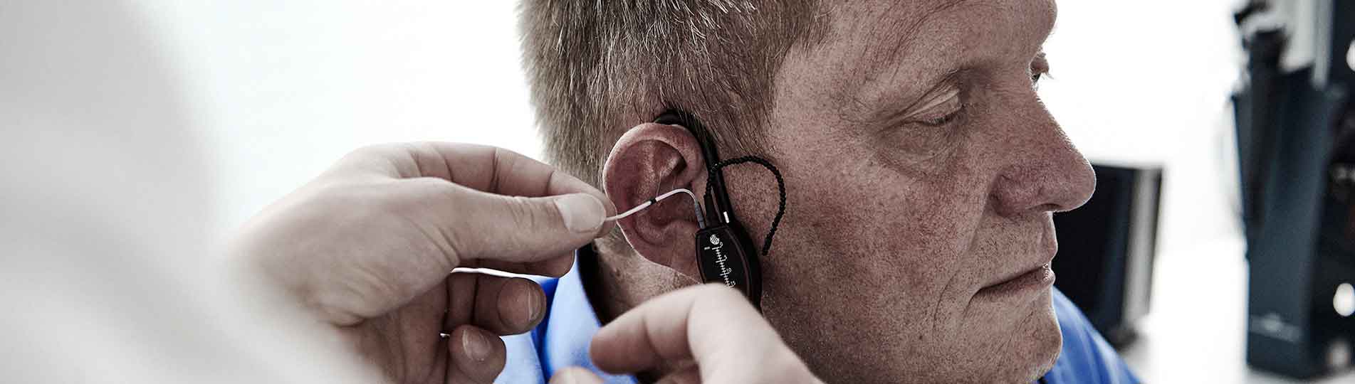 Male clinician inserting in-situ probe tube into male client's ear