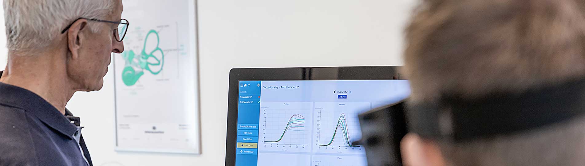 Male clinician and male patient looking toward screen with Saccadometry results