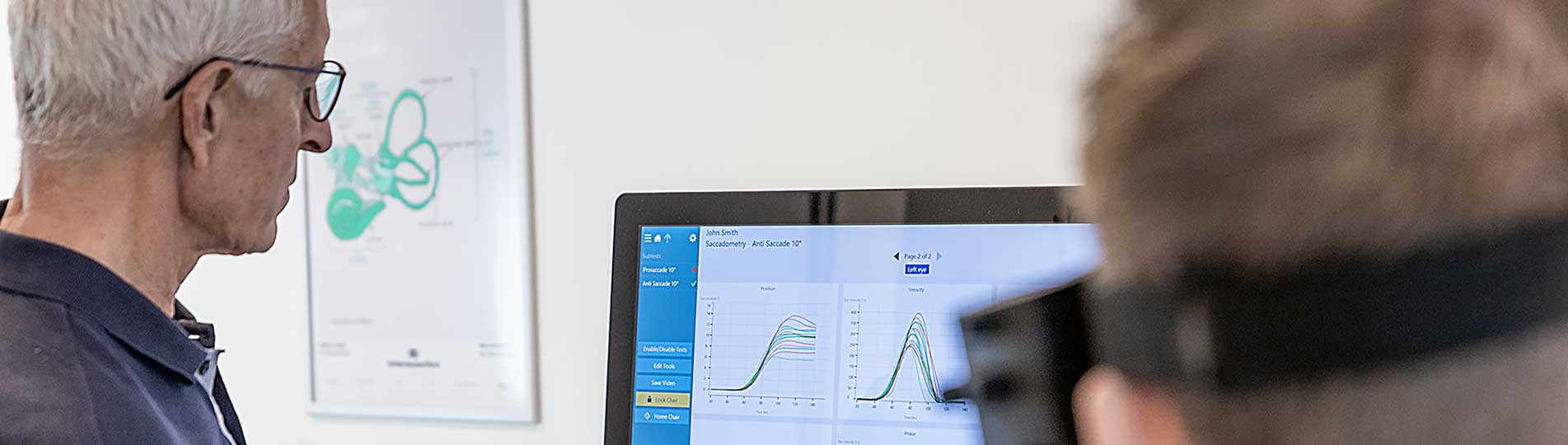 Male clinician and male patient looking at saccadometry software display on computer screen