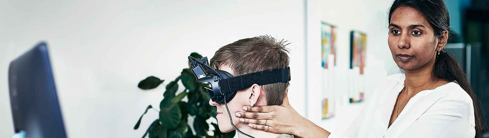 Female clinician performing head impulses on male patient